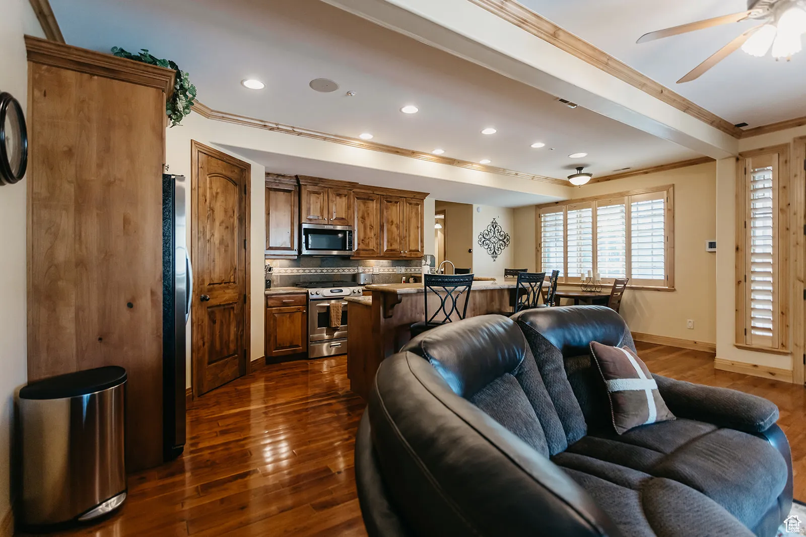 Open-concept living area featuring rich wood-finish flooring, recessed lighting, and wooden ceiling beams