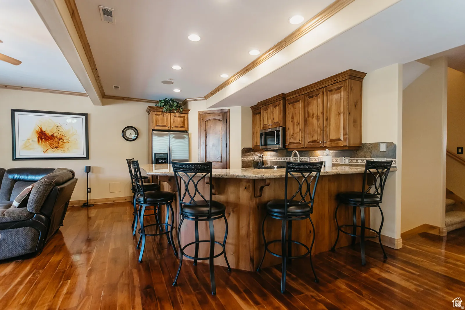 Full kitchen bar with wood cabinetry, granite countertops, and stainless steel appliances