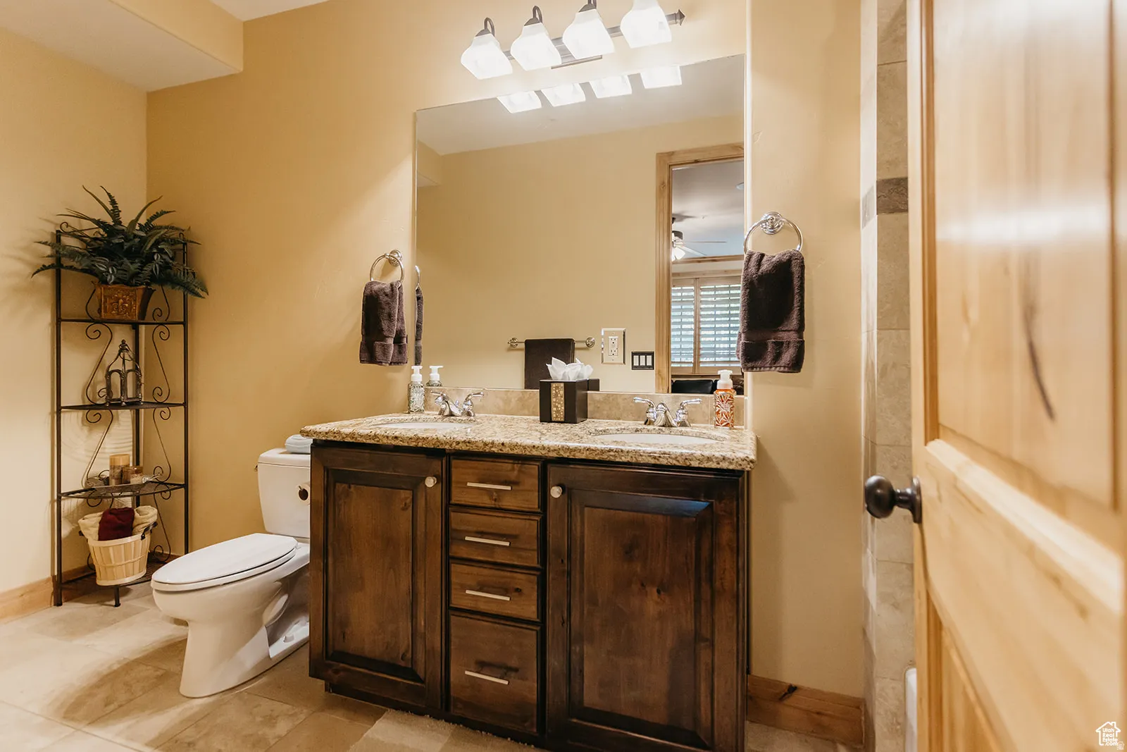Bathroom featuring a double vanity with a stone countertop, dual undermount sinks, and a framed mirror