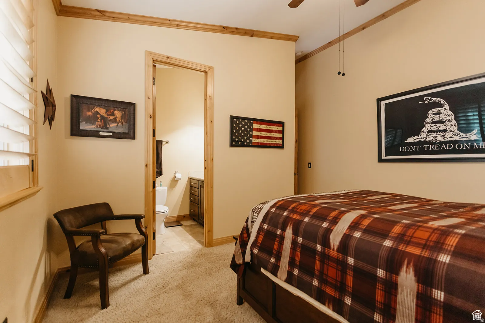 Carpeted room with wood trim and an open doorway revealing a bathroom with a toilet and vanity