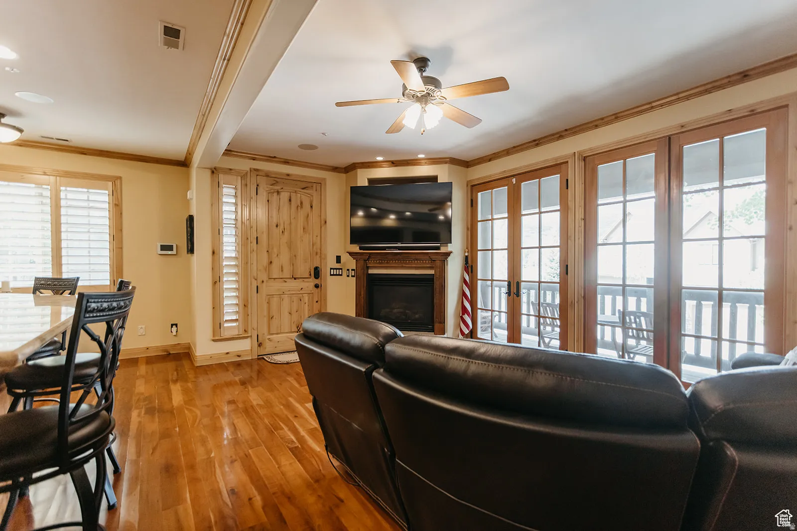 Living area featuring wood-finish flooring, a corner fireplace with a wooden mantel, and a ceiling fan