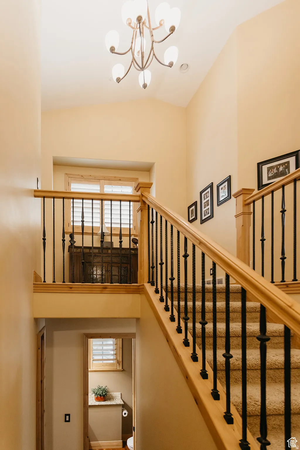 Staircase with carpeted treads, wood handrails, and wrought iron balusters