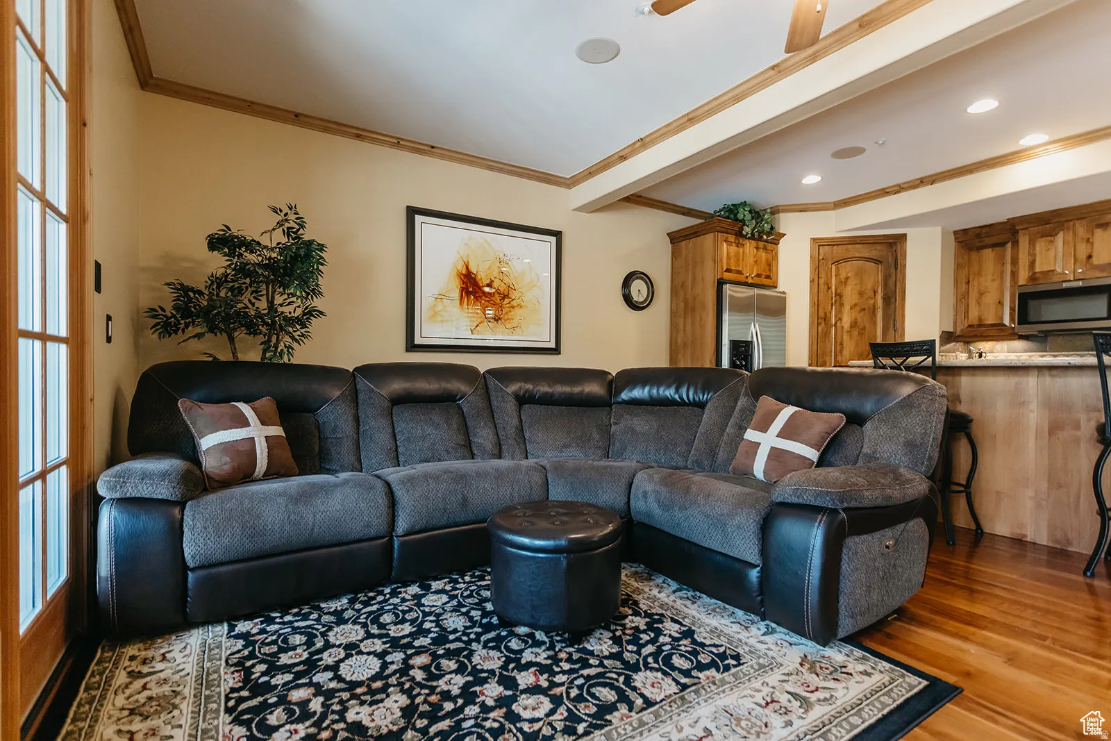 Open-concept living space featuring wood-finish flooring and crown molding