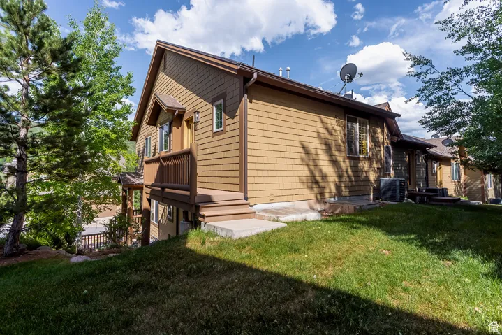 Exterior featuring tan shingle siding, brown trim, a covered entry with a railing, and multiple windows