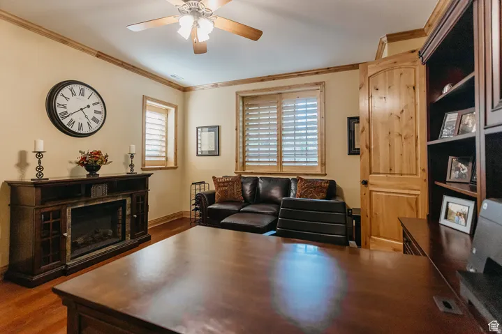 Warmly appointed room featuring wood-finish flooring, wood trim, and a ceiling fan with integrated lighting