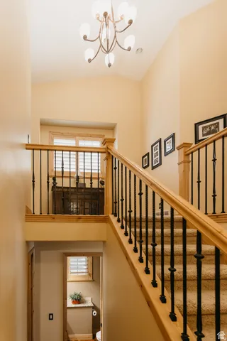 Staircase with carpeted treads, wood handrails, and wrought iron balusters