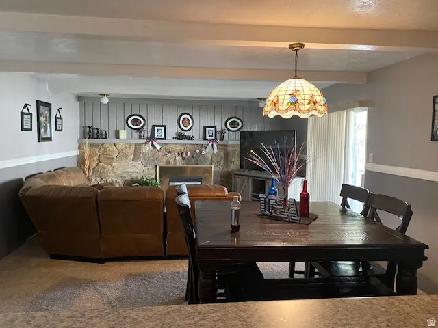 Living area featuring a stone fireplace with a brass insert, a wooden mantel, and vertical paneling