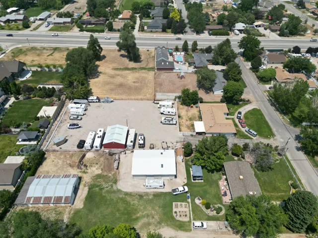 Expansive aerial perspective showcasing a property with significant open land, multiple structures, and paved areas