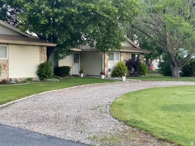 Gravel driveway accessing a home with beige siding and stone accents