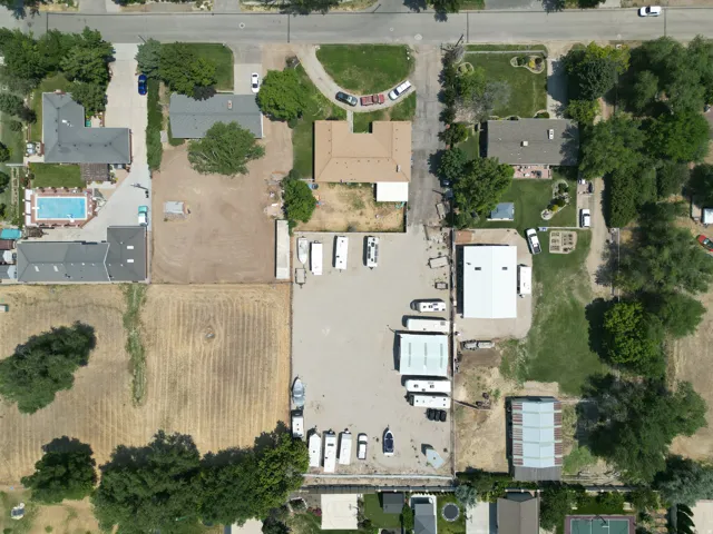 Aerial view of a large lot featuring a substantial paved area with multiple structures, including a prominent warehouse-style building