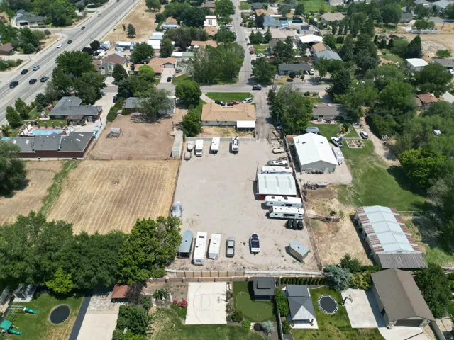 Expansive gravel lot featuring a large metal-sided building with a white roof and multiple outbuildings