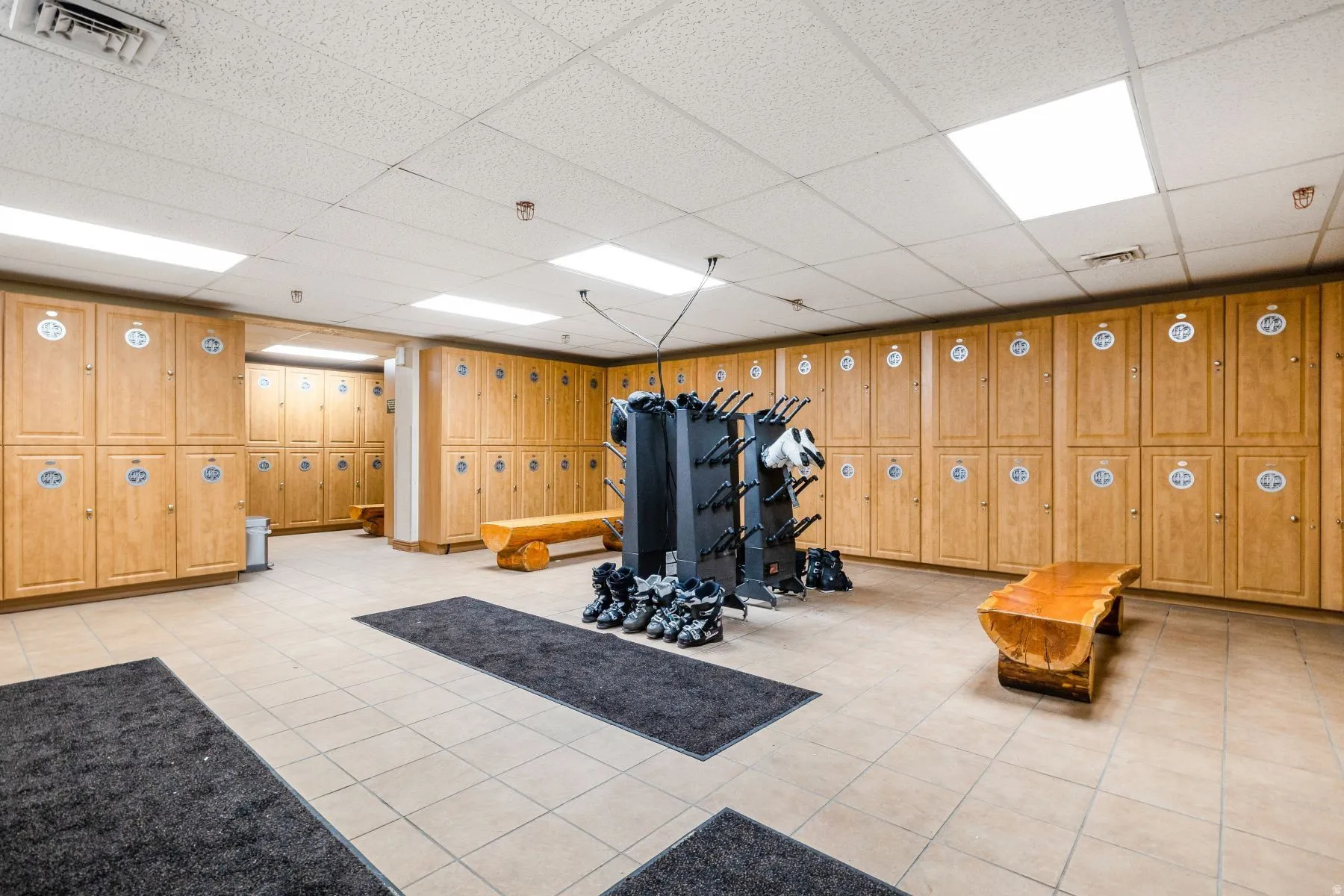 Locker room featuring extensive wood-finish cabinetry, tile flooring, and integrated overhead lighting