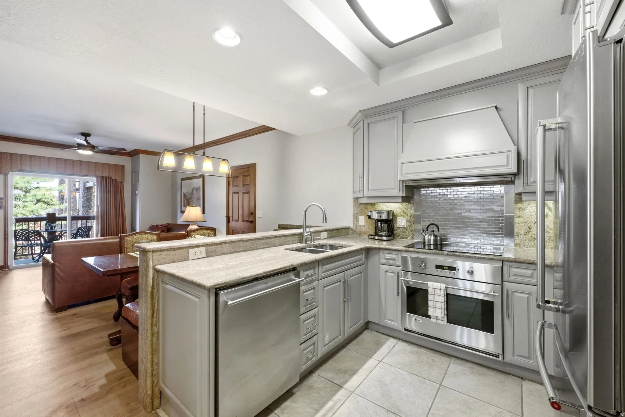Modern kitchen featuring gray cabinetry, granite countertops, and stainless steel appliances