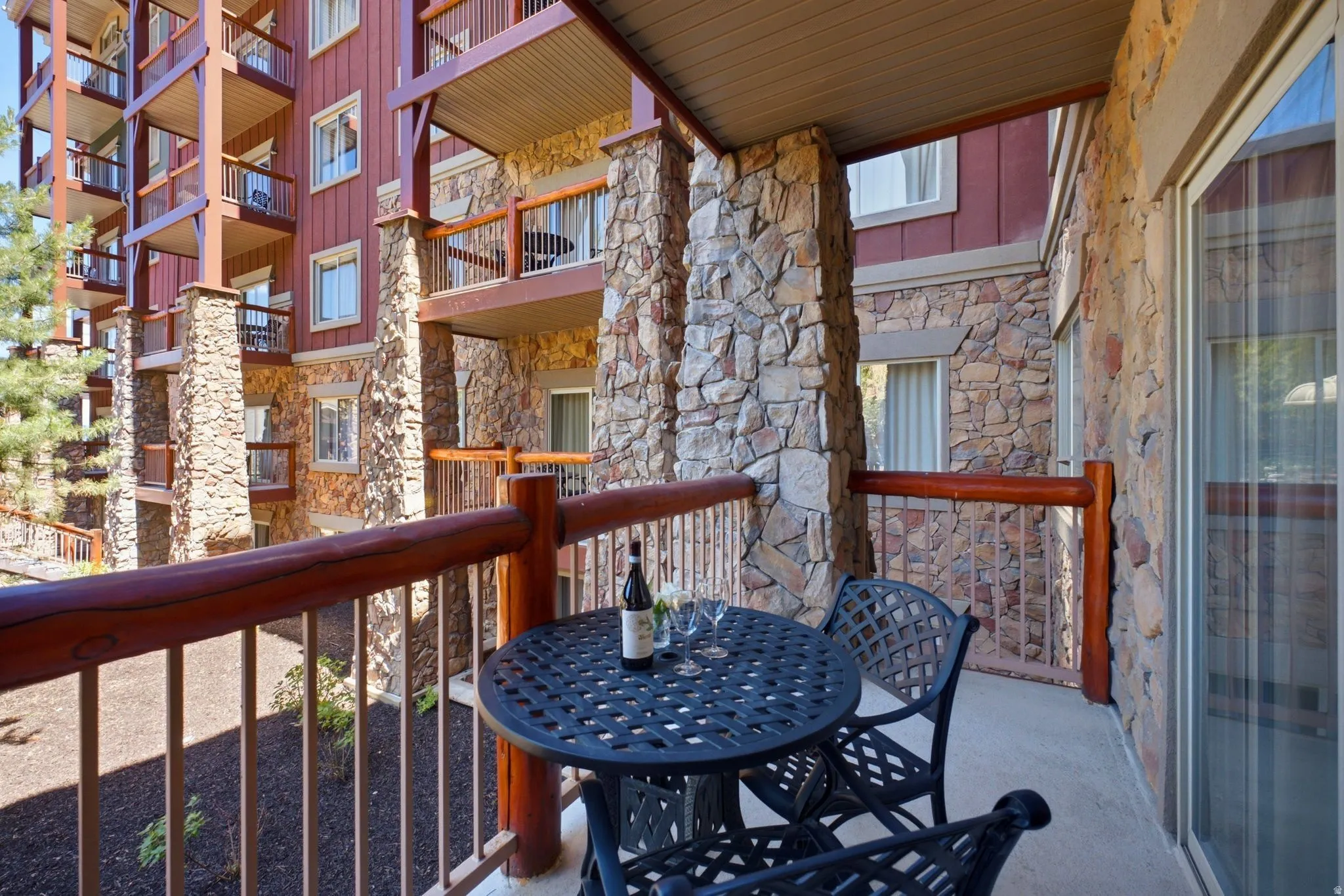 Private balcony featuring log-style railings and stone veneer pillars
