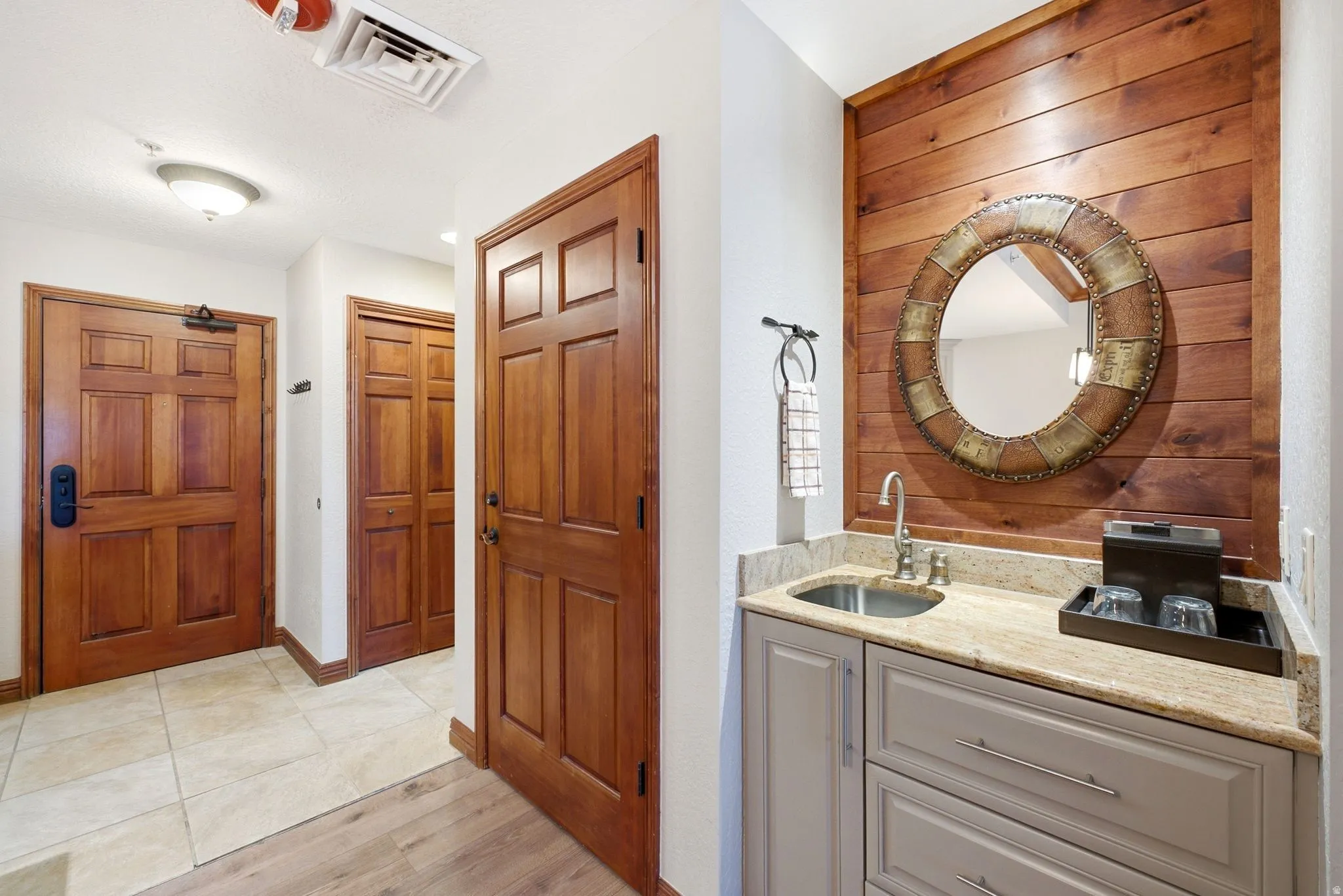 Wet bar with wood-finish paneling, stone countertop, and under-mount sink