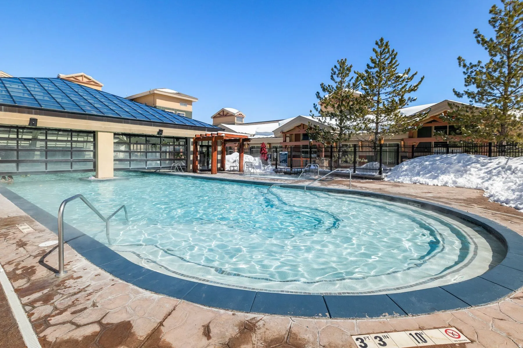 Outdoor pool with integrated steps, surrounded by stone-finish decking
