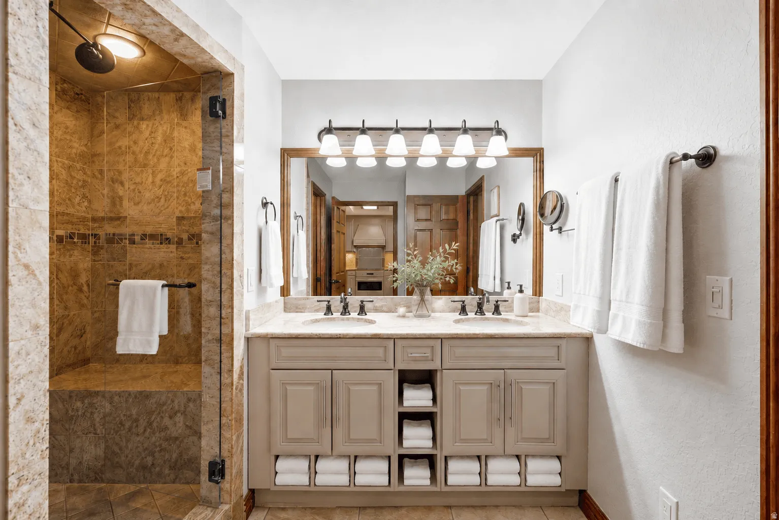 Dual sink vanity with stone countertop, built-in storage, and framed mirror