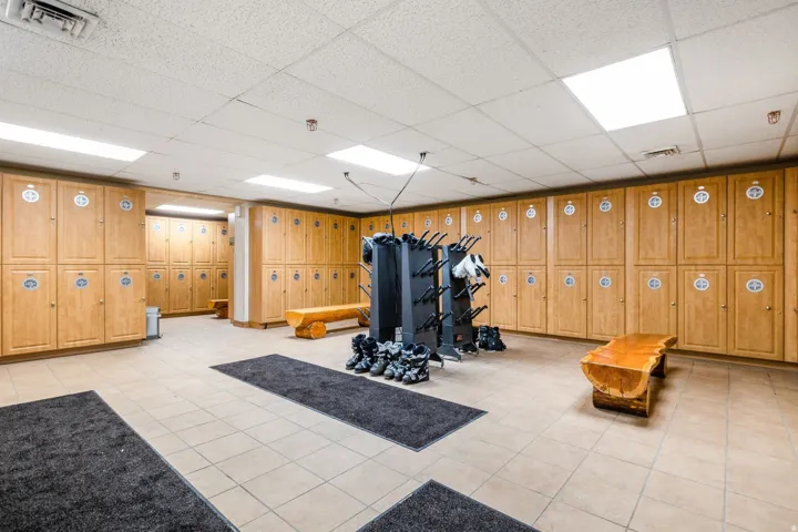 Locker room featuring extensive wood-finish cabinetry, tile flooring, and integrated overhead lighting