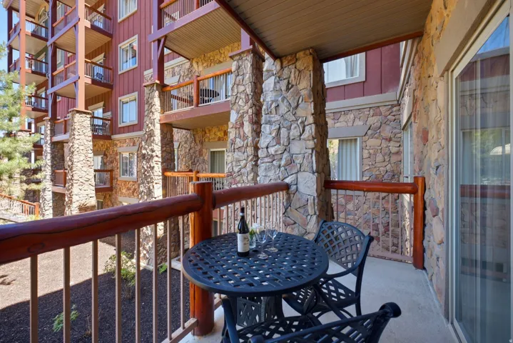 Private balcony featuring log-style railings and stone veneer pillars