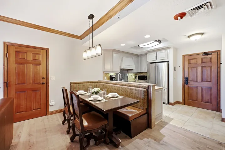 Open-concept kitchen and dining area featuring light wood-finish flooring, a built-in banquette, light-toned cabinetry, and stainless steel appliances