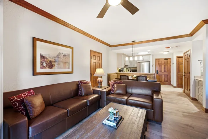 Open-concept living space with wood-finish flooring, crown molding, and a ceiling fan