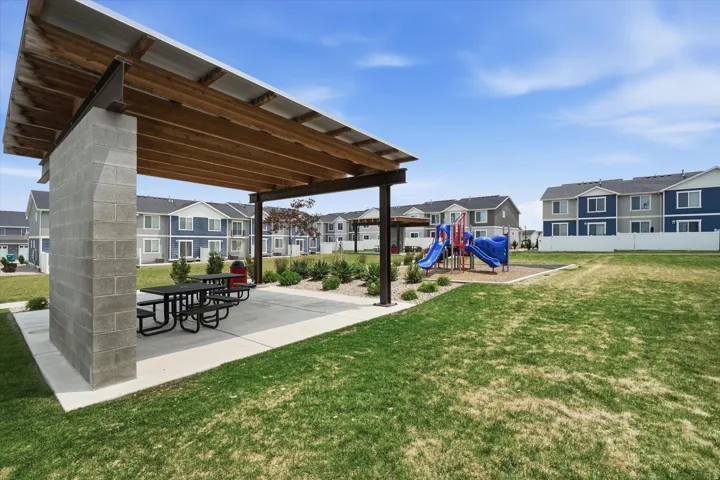 Outdoor recreational area featuring a covered patio with concrete flooring, supported by concrete block walls and metal beams, and a wood-slat ceiling