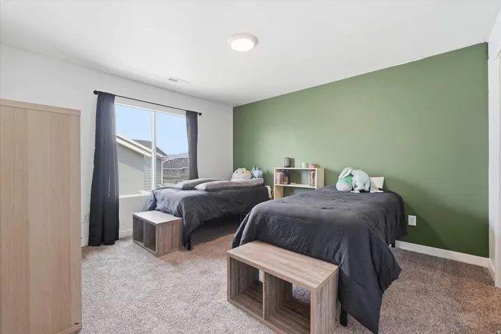 Bedroom featuring a prominent green accent wall and light gray carpeting