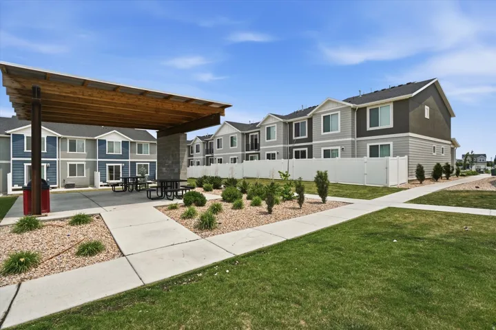 Outdoor common area featuring a modern wood pergola, concrete patio, and multiple picnic tables