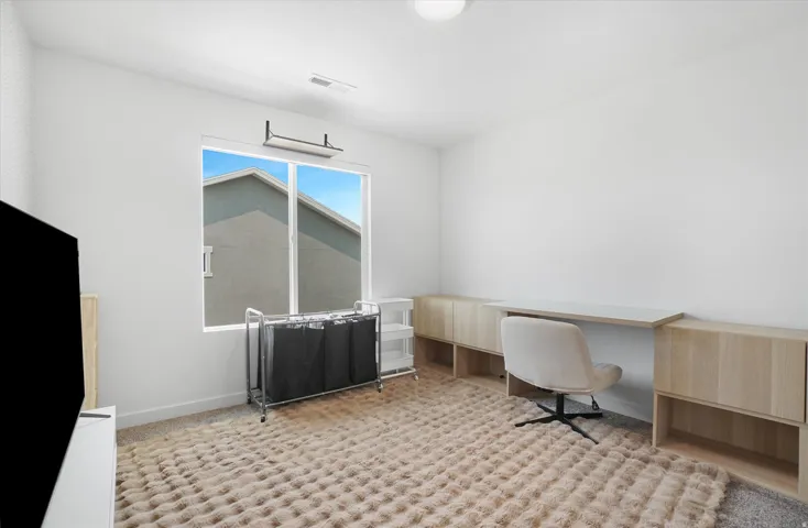 Bright room with a large window and light-toned carpet flooring
