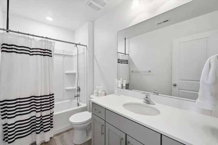 Bathroom featuring a white tub/shower combination with wall-mounted fixtures