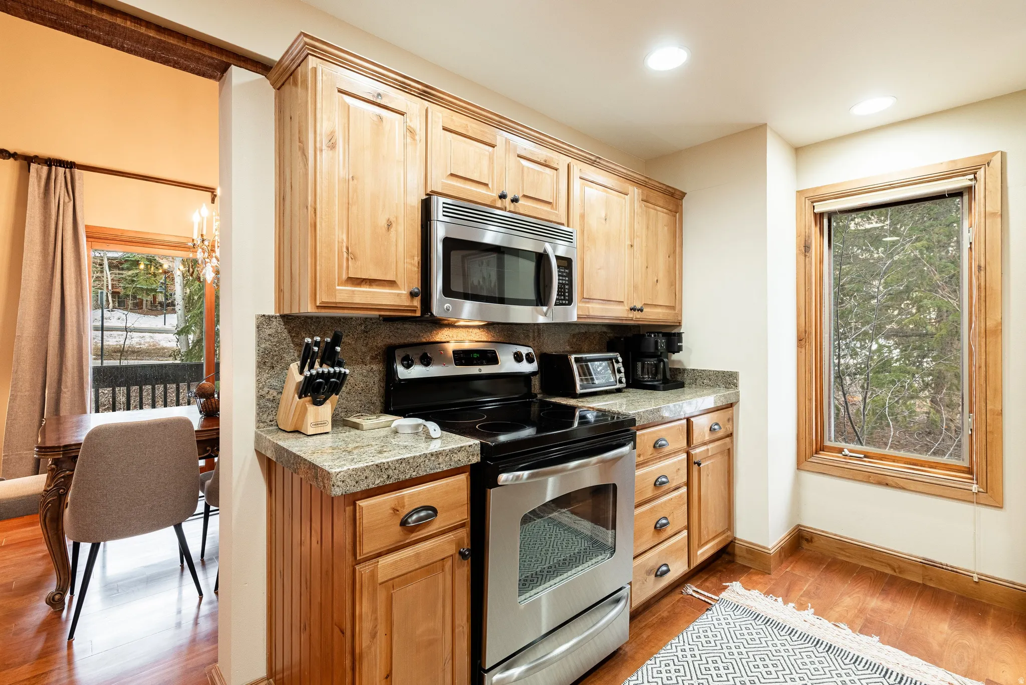 Kitchen featuring light wood cabinetry, stone countertops, stainless steel appliances, wood-finish flooring, and recessed lighting