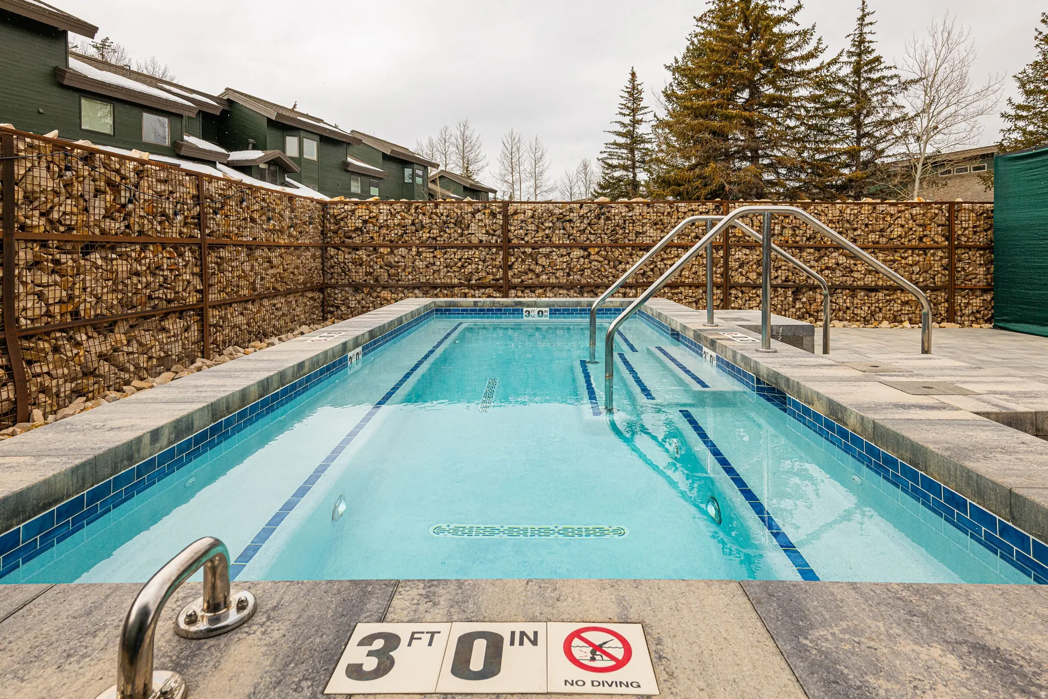Rectangular swimming pool with light blue water and dark blue tile accents