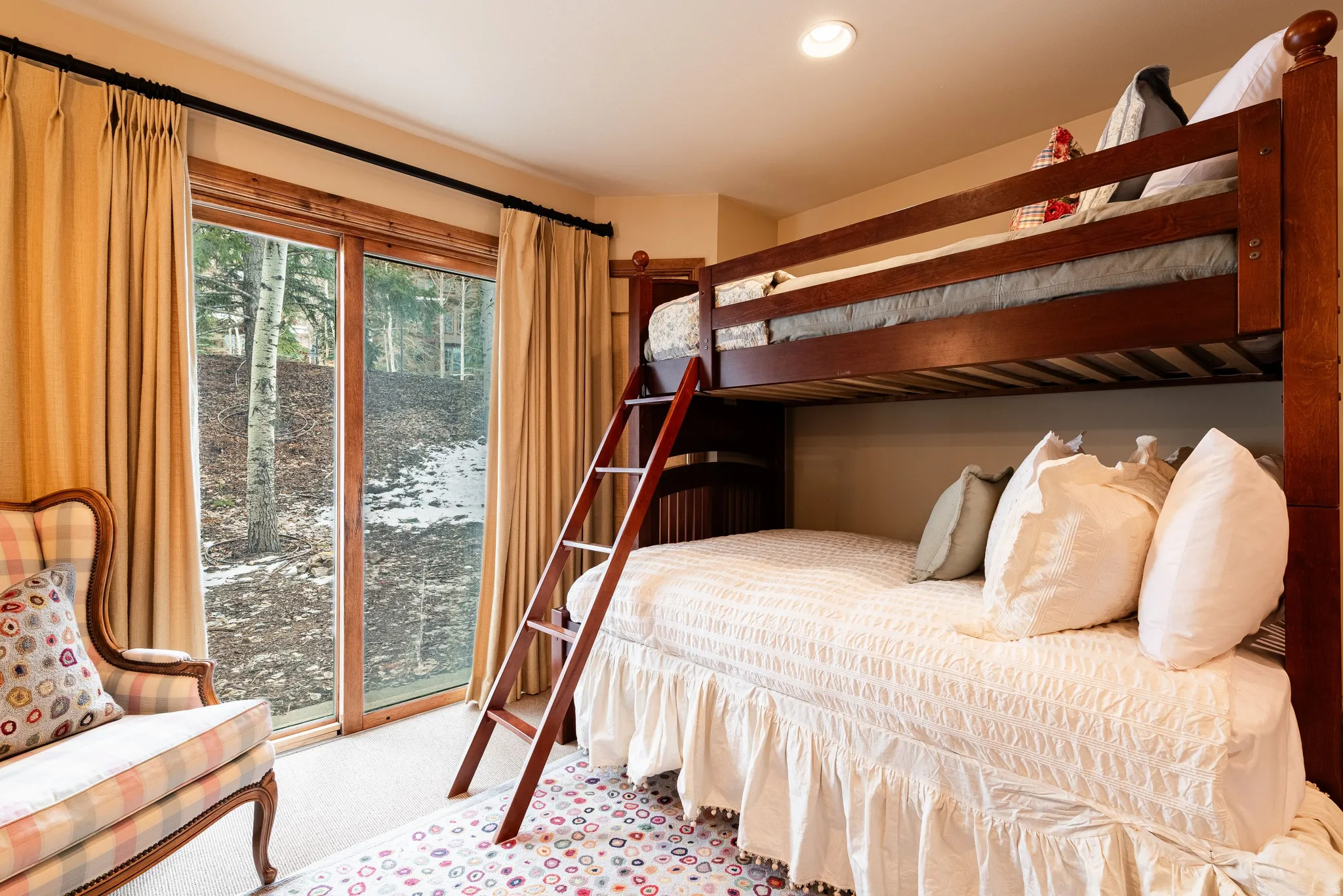 Room featuring a wood-finish bunk bed frame with integrated ladder, recessed ceiling lighting, and a sliding glass door with wood trim