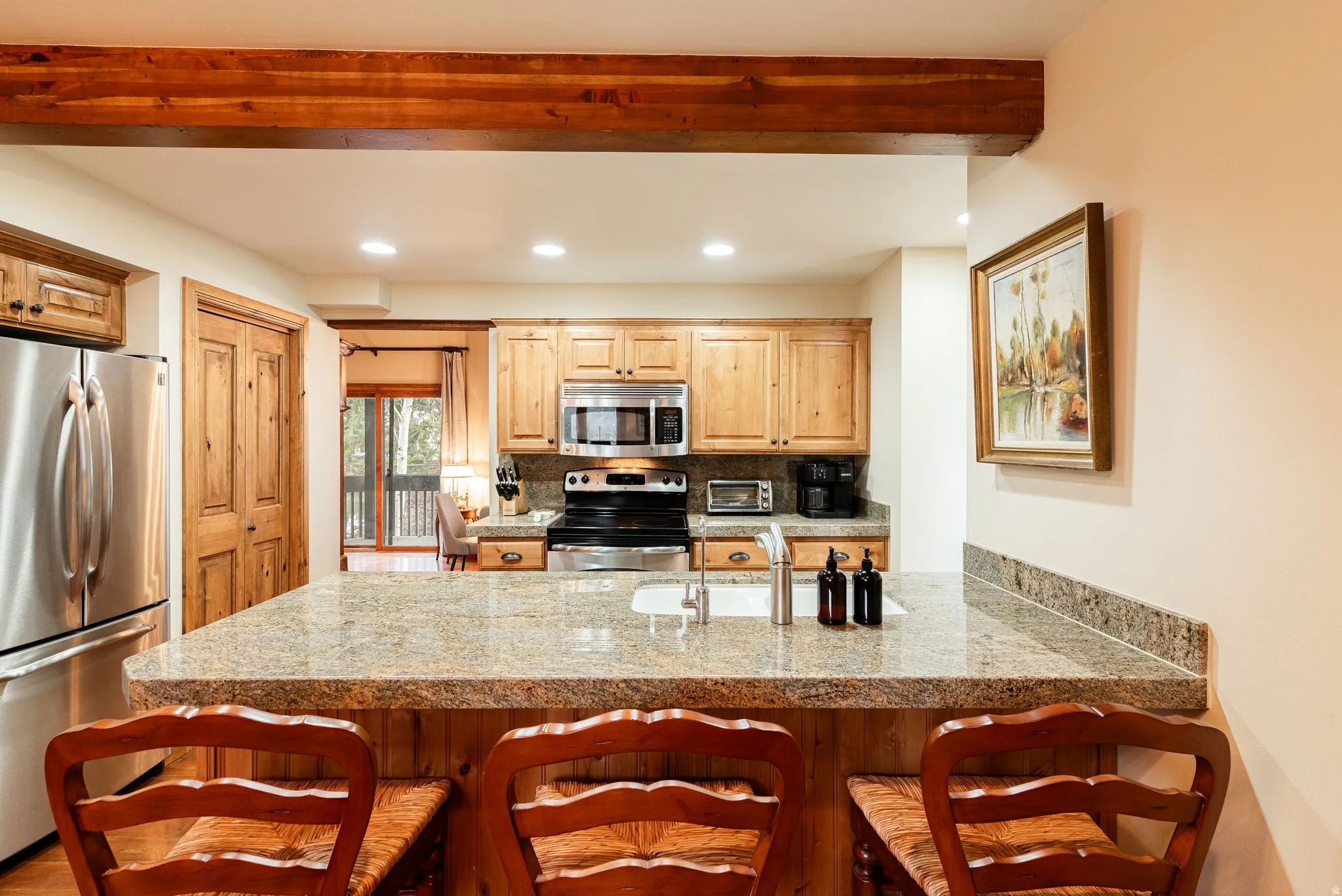 Kitchen featuring granite countertops, stainless steel appliances, recessed lighting, wood cabinetry, and a breakfast bar with paneling