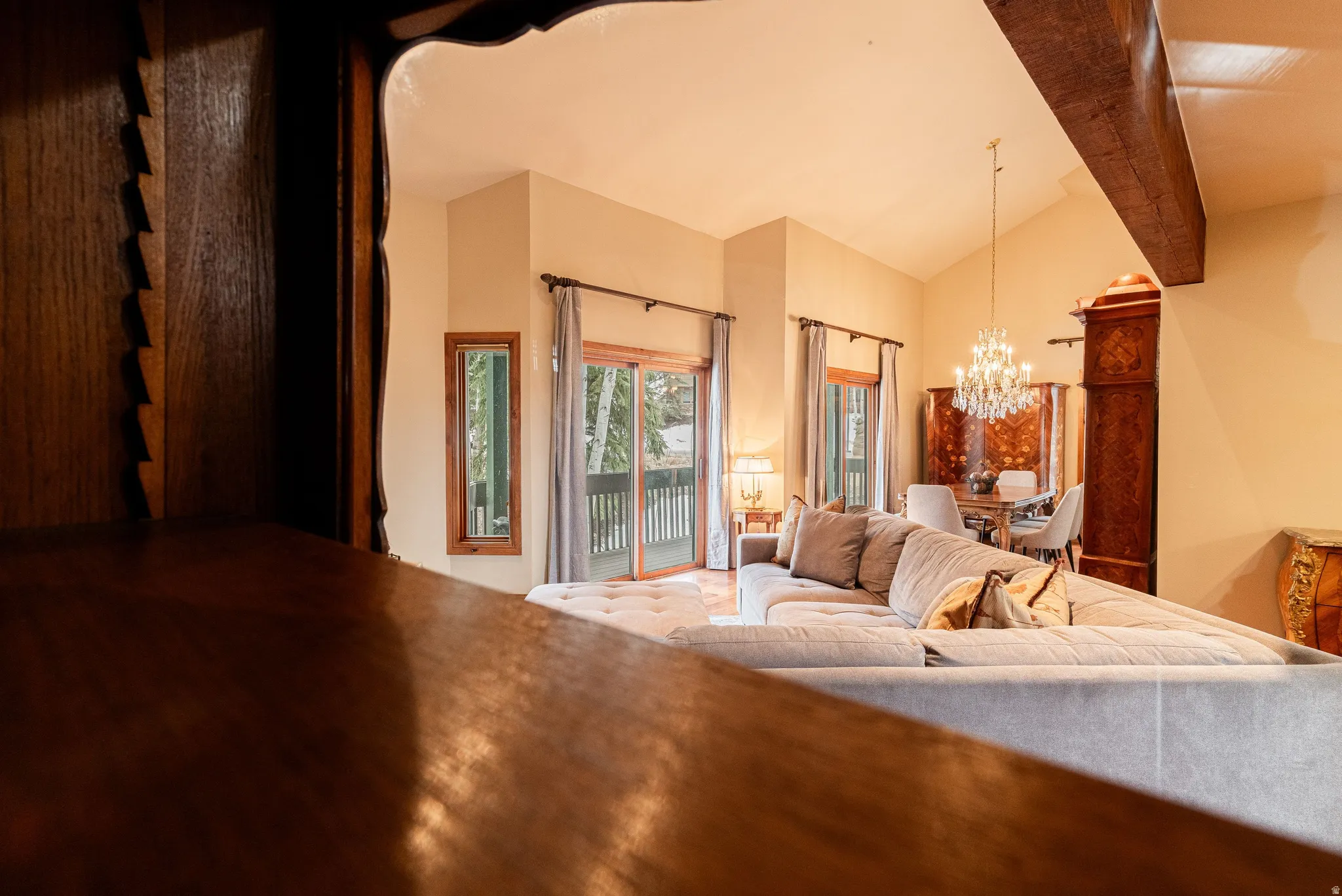 Spacious living area featuring vaulted ceilings, exposed wood beam, and wood-finish flooring