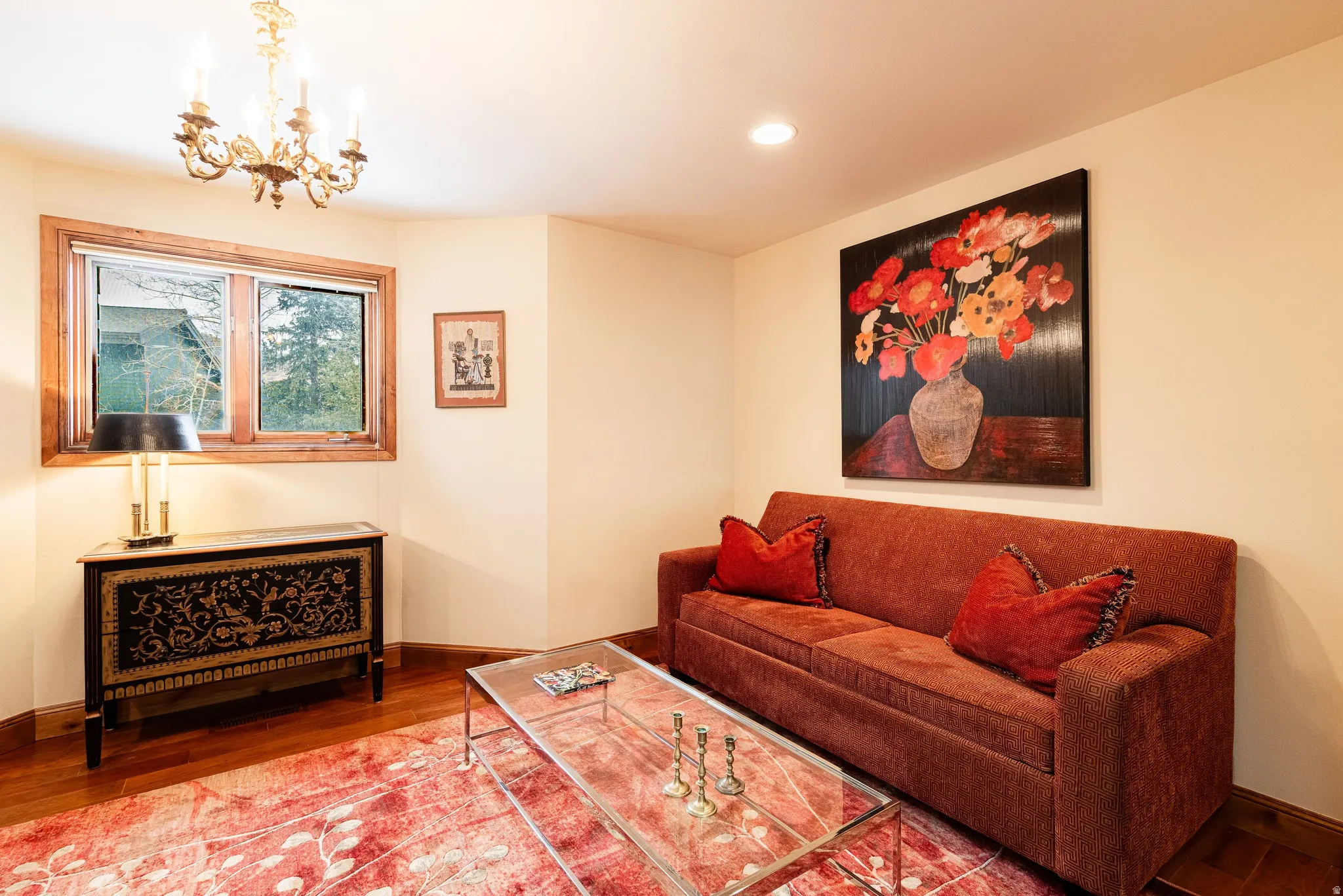 Hardwood flooring throughout, featuring a window with natural wood trim, recessed lighting, and a chandelier