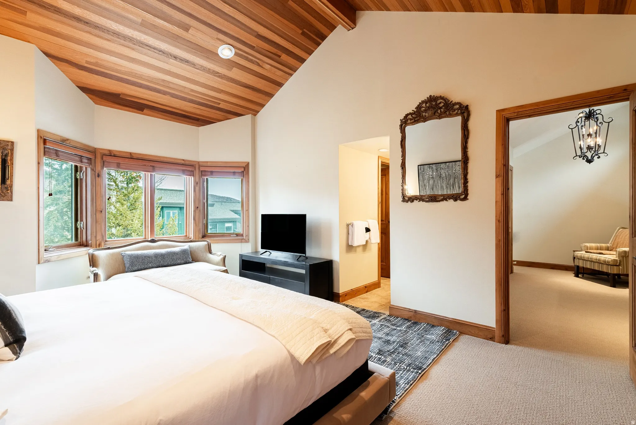 Vaulted wood-paneled ceiling accentuates this bedroom featuring a bay window with wood trim