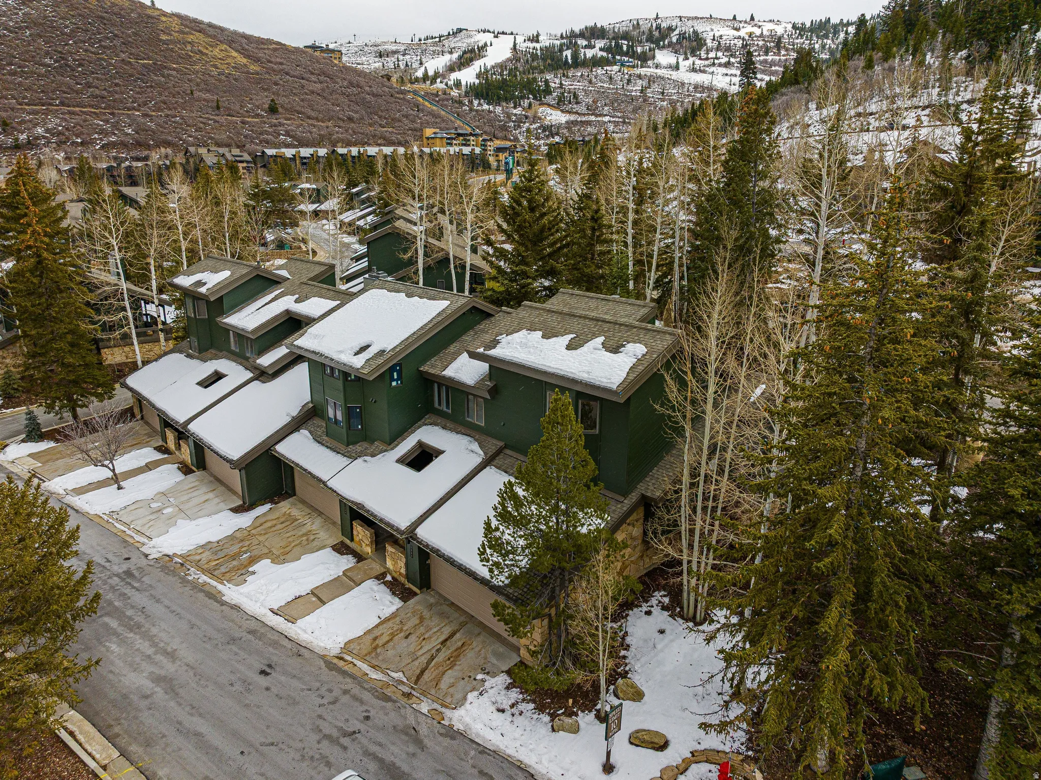Townhome community featuring multi-story units with deep green siding, attached garages, and pitched roofs