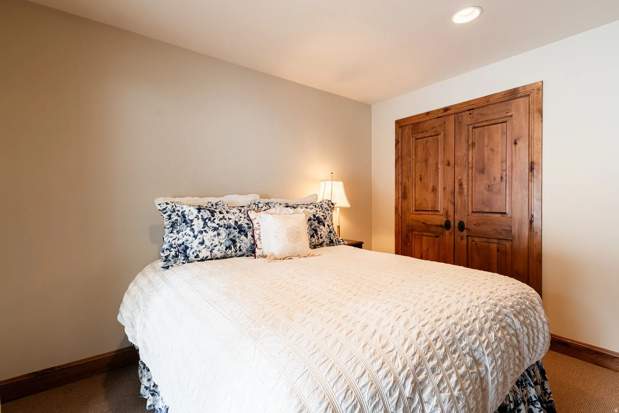 Bedroom featuring neutral wall paint, recessed ceiling lighting, wood-finish baseboards, and wood-panel closet doors with matte black hardware