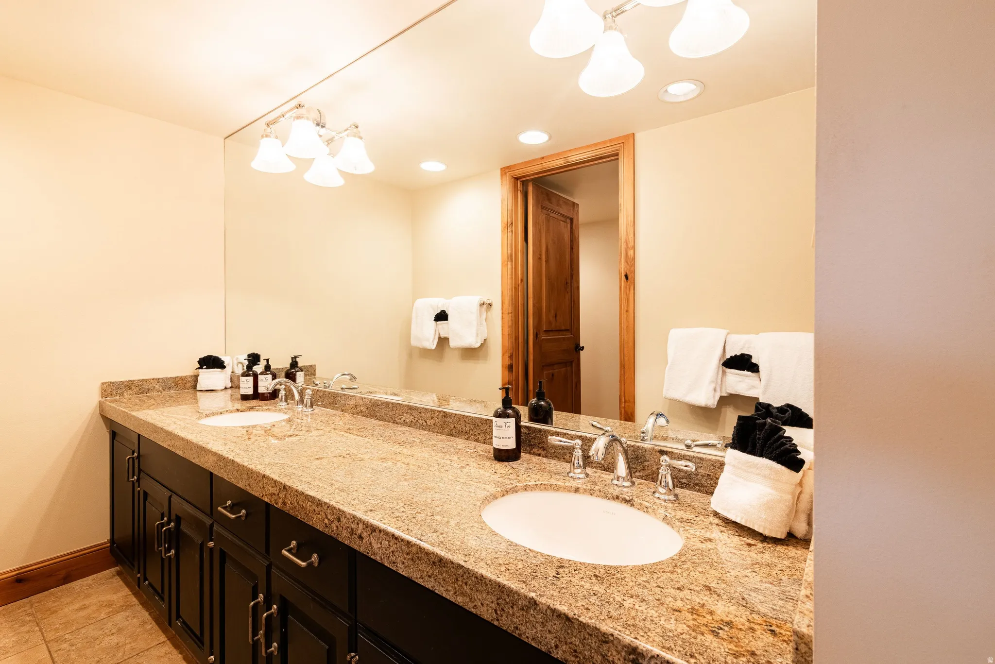 Double vanity featuring a granite-finish countertop, dual undermount sinks, and dark wood-finish cabinetry with silver-tone hardware
