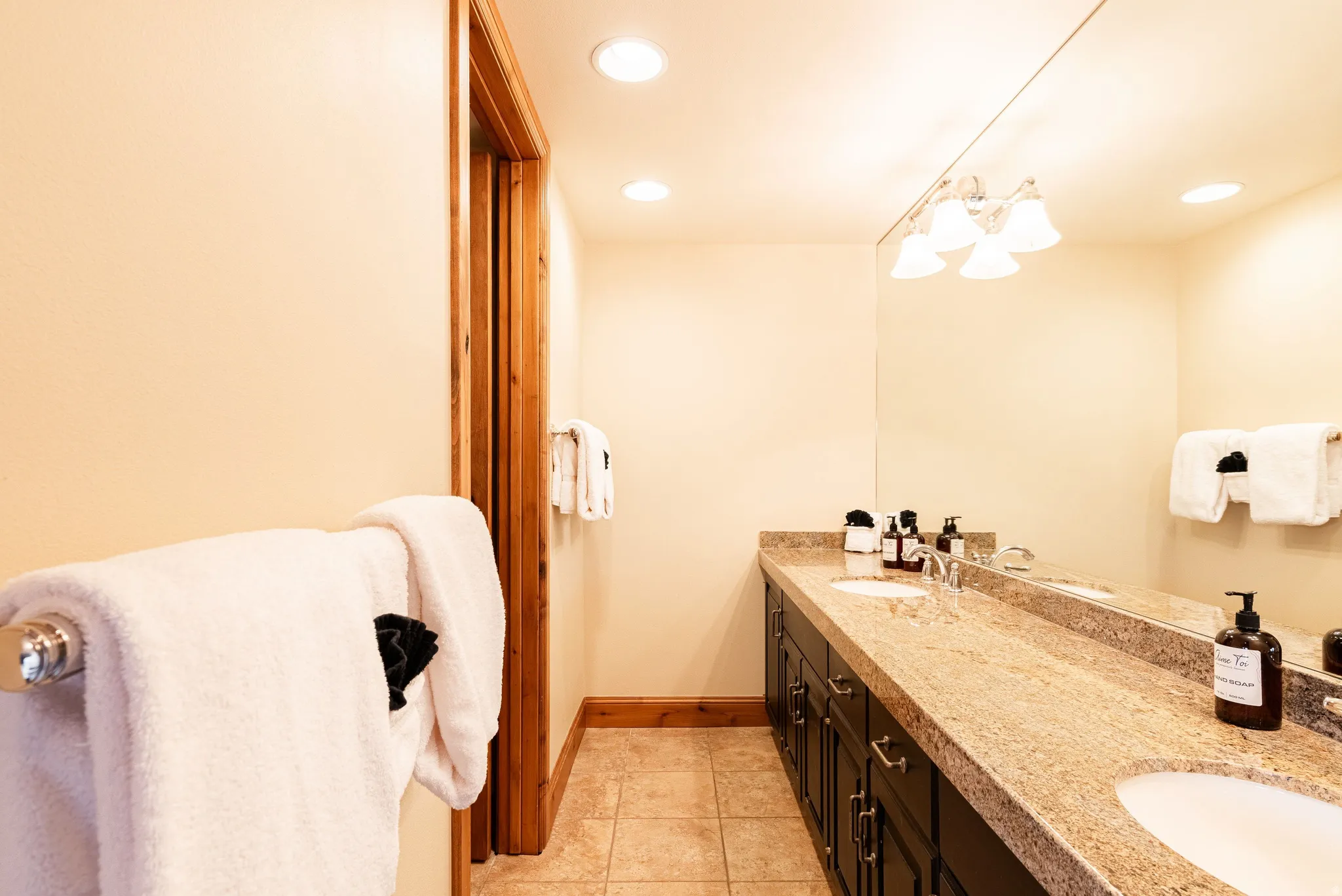 Double vanity with undermount sinks, granite countertop, and dark wood cabinetry