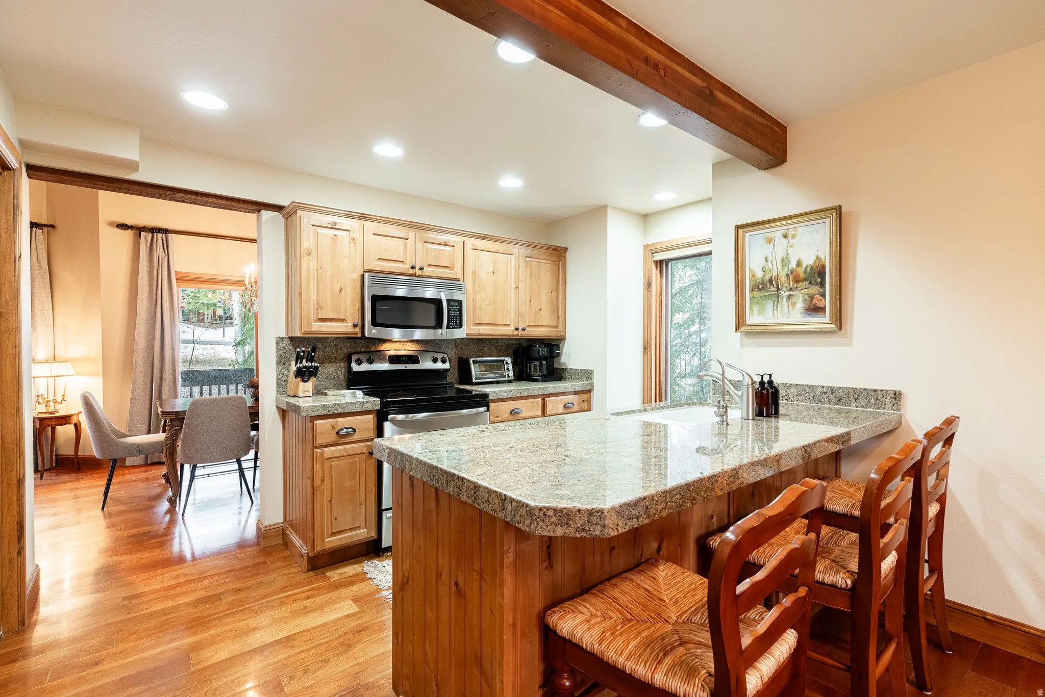 Kitchen featuring wood cabinetry, stainless steel appliances, and a granite-finish countertop with a breakfast bar
