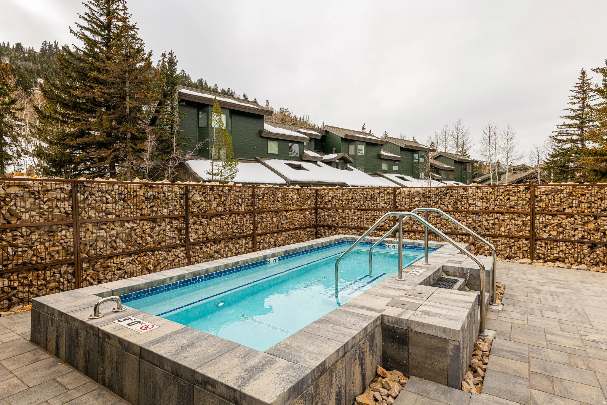 Outdoor swimming pool with integrated spa and stone paver surround