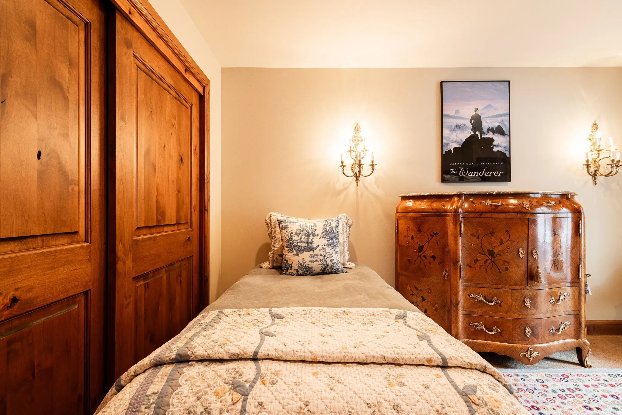 Built-in wooden closet with panel doors, neutral wall paint, and decorative wall sconces