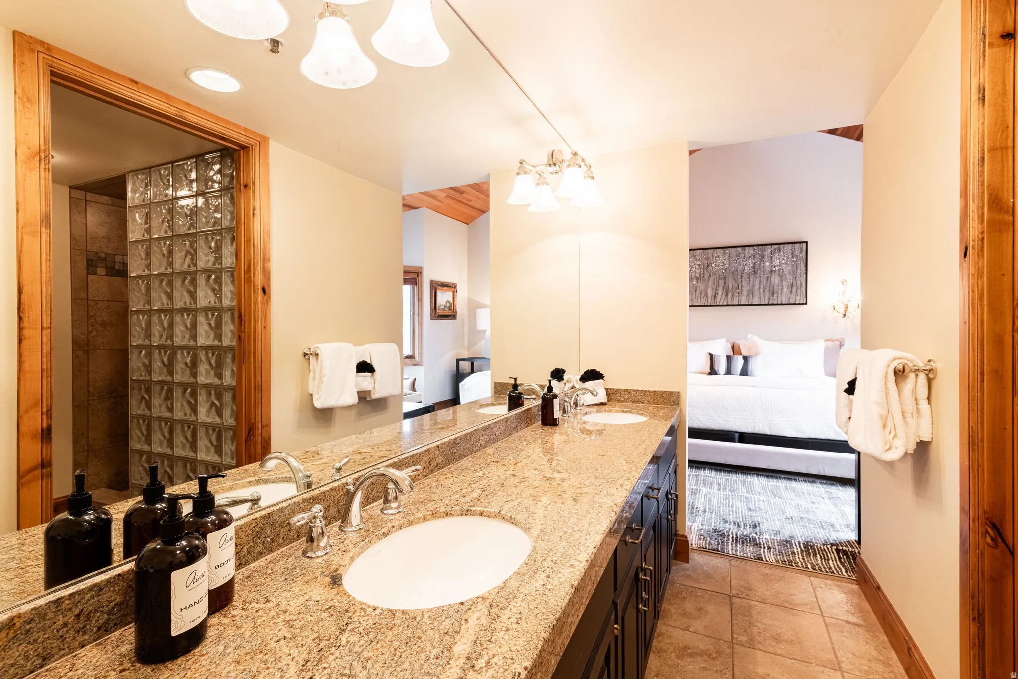 Double vanity with granite countertop, integrated sinks, chrome fixtures, and a large mirror