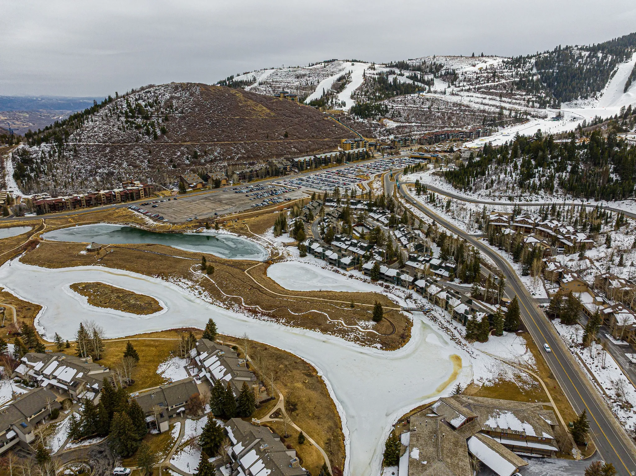 Aerial perspective showcasing multiple residential structures, snow-covered mountains, and a network of roads