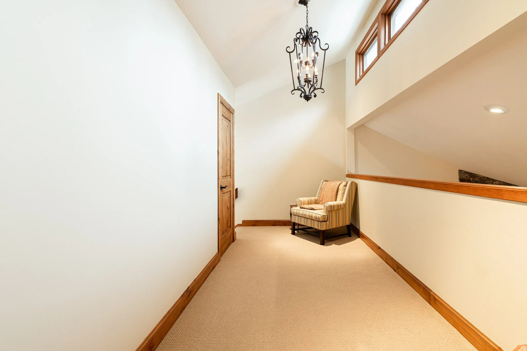 Hallway featuring wood-finish trim, a recessed ceiling, and a prominent chandelier