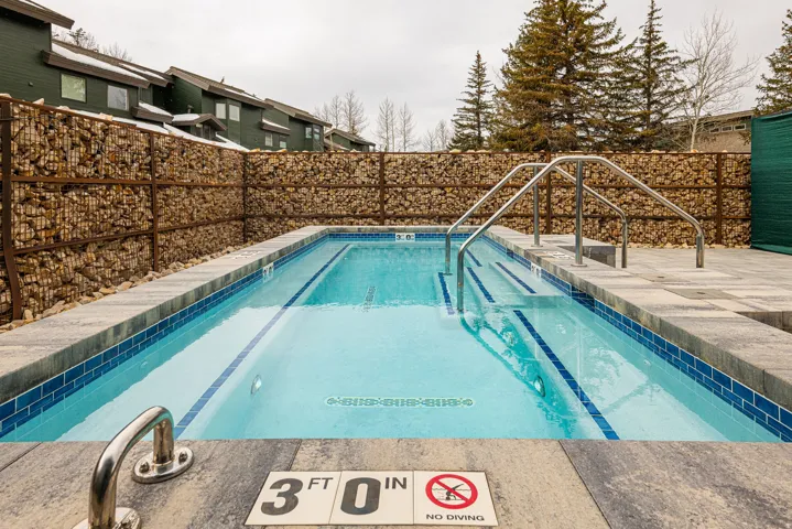 Rectangular swimming pool with light blue water and dark blue tile accents