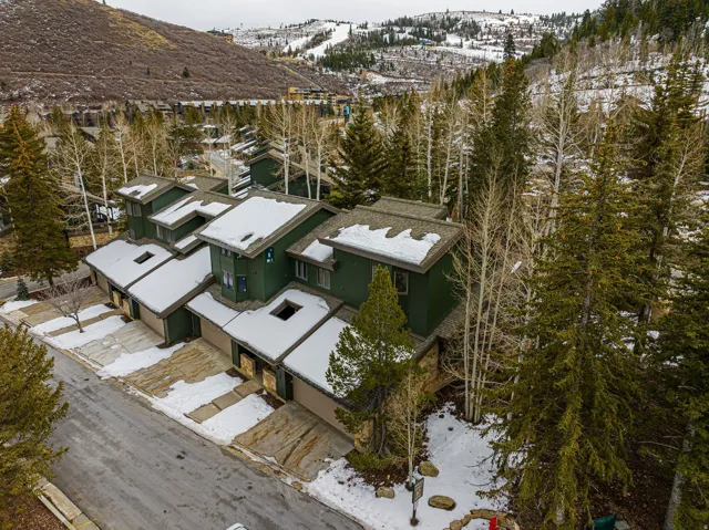 Townhome community featuring multi-story units with deep green siding, attached garages, and pitched roofs