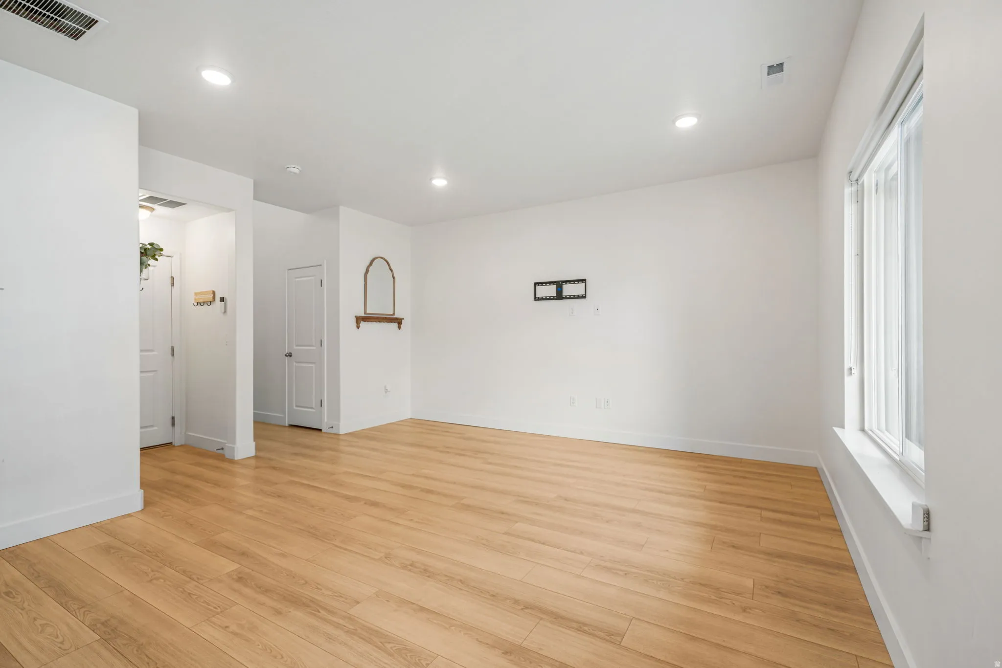 Spacious interior featuring wood-finish flooring, recessed lighting, and a large window providing natural illumination